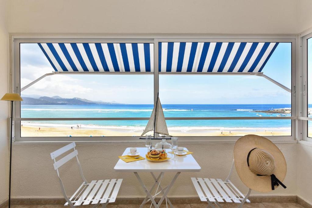 a table and chairs with a view of the beach at Las Canteras Seafront Apartment in Las Palmas de Gran Canaria