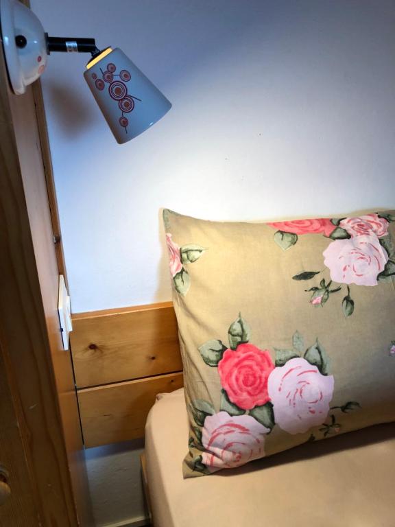 a pillow with pink roses on it sitting on a bed at Civico 10 in Candide