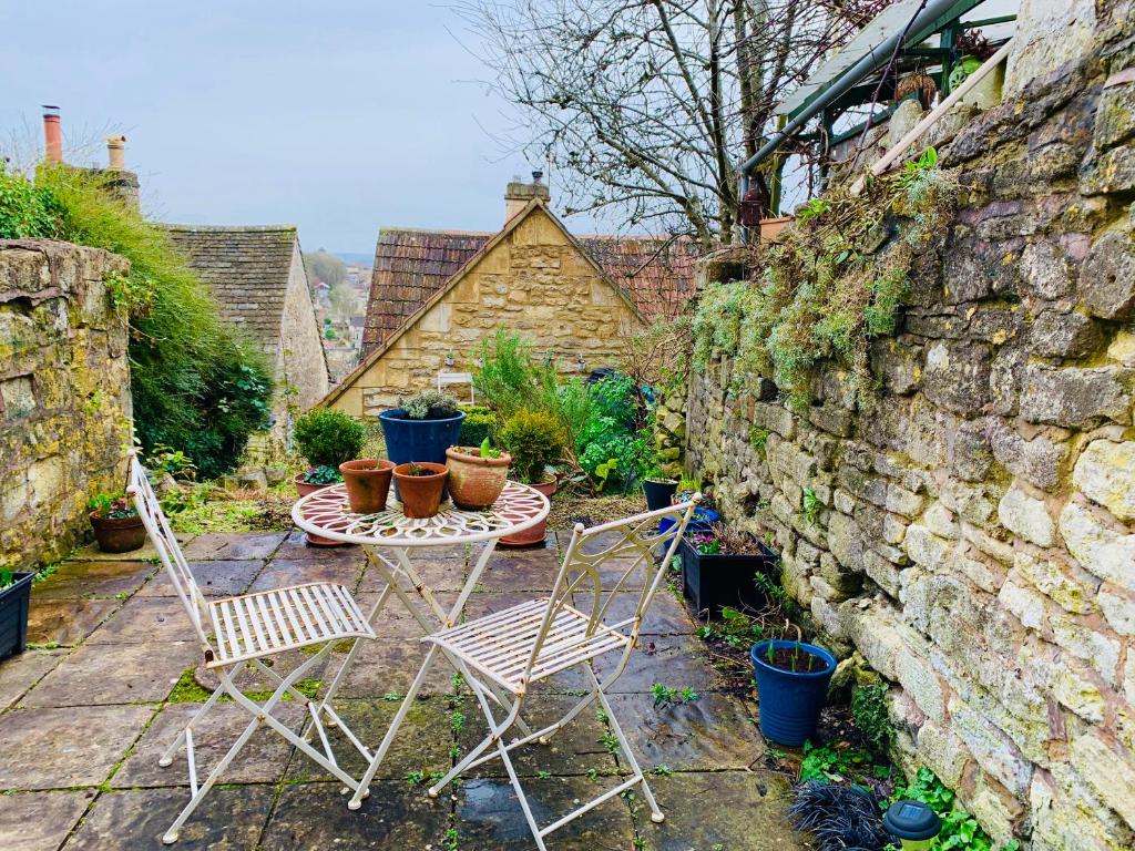 two chairs and a table in front of a stone wall at Weaver's Cottage @ Number 10 in Bradford on Avon