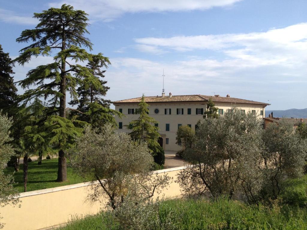 un gran edificio blanco con árboles en el primer plano en Fattoria Di Cavaglioni en San Rocco a Pilli