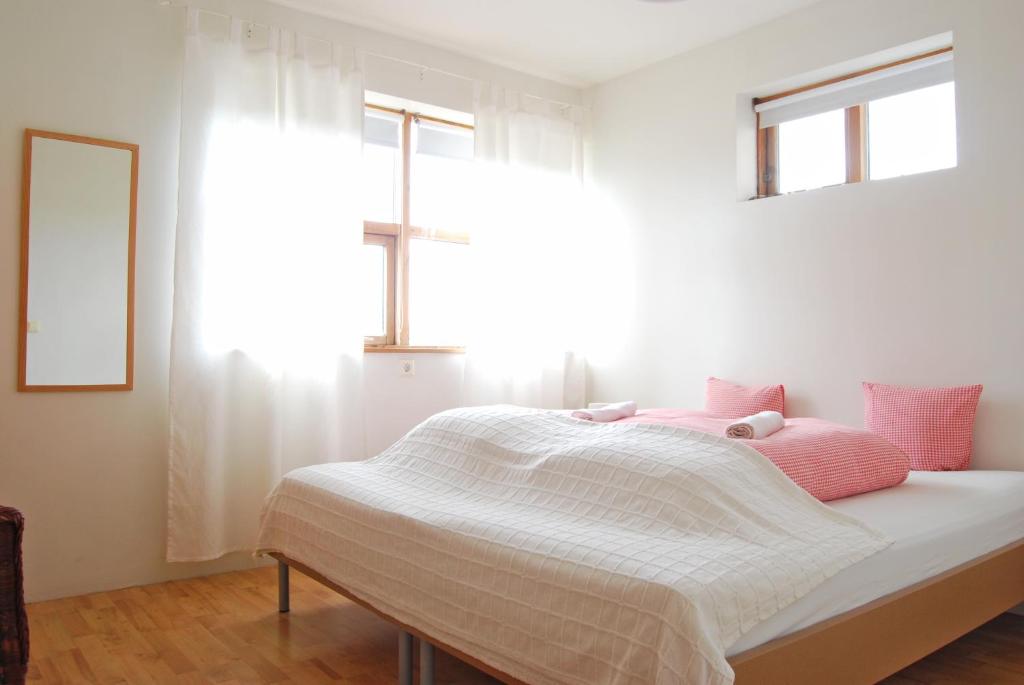 a white bedroom with a bed with pink pillows at Guesthouse Vestri-Gardsauki in Hvolsvöllur