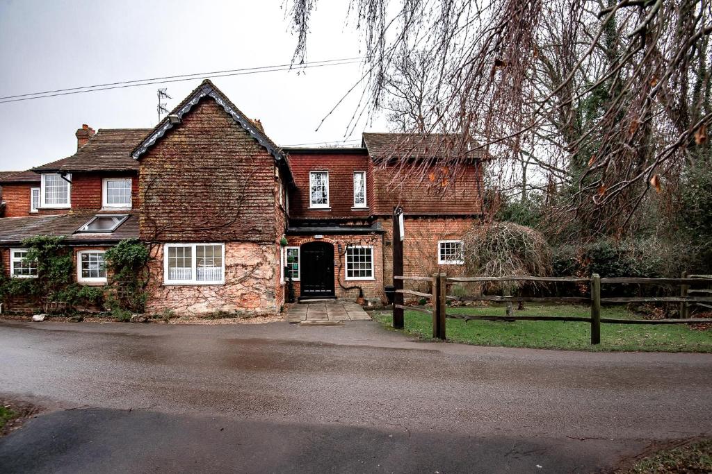 une vieille maison en briques avec une clôture devant elle dans l'établissement Trivelles Waterhall Country Gatwick Hotel & airport parking, à Crawley