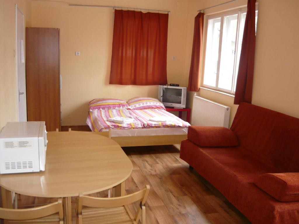 ゼベゲーニにあるBörzsöny Kapuja Vendégházのベッド、テーブル、ソファが備わる小さな客室です。