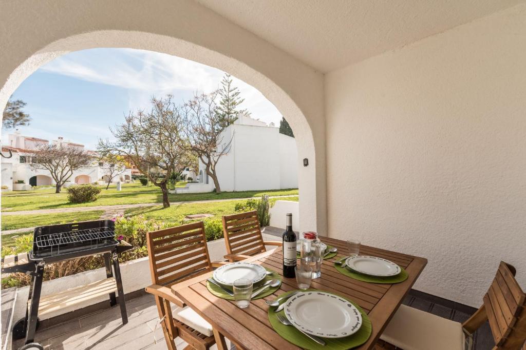 una mesa de madera con sillas y una parrilla en el patio en LovelyStay - Green Oasis Villa, en Vilamoura