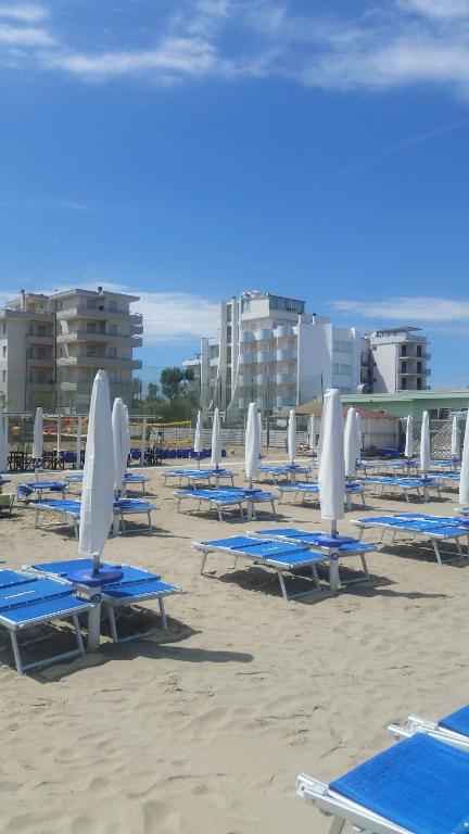 Hotel Marco في ليدو دي سافيو: مجموعة من كراسي الشاطئ والمظلات على الشاطئ