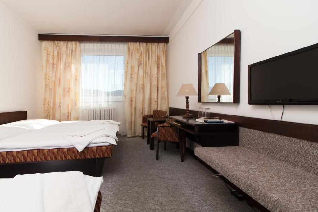 a hotel room with a bed and a desk and a television at Hotel Merkur - Jablonec nad Nisou in Jablonec nad Nisou