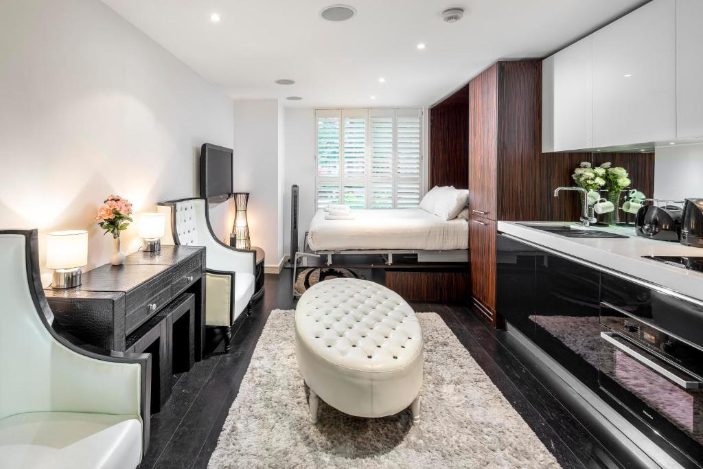 um quarto com uma cama e uma cozinha com um lavatório em ALTIDO Luxury Studio in Chelsea, close to Sloane Square and Victoria station em Londres