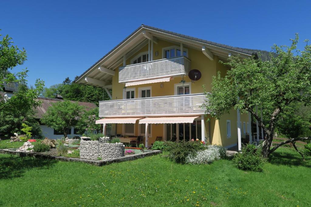 ein gelbes Haus mit einem Balkon auf einem Hof in der Unterkunft Ferienwohnung Reiteralmblick - Regina Häusl in Schneizlreuth