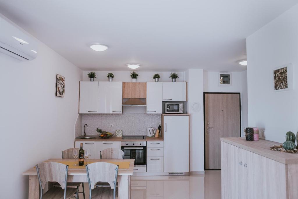 a kitchen with white cabinets and a table with chairs at Poolside Hideout Apartments in Novalja