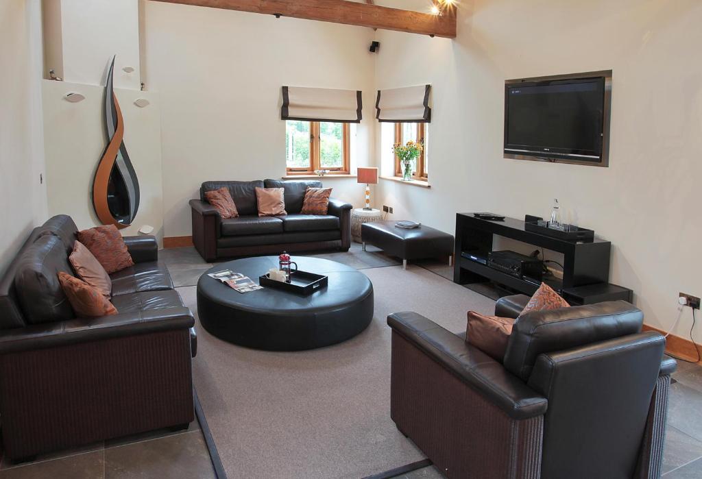 een woonkamer met lederen meubels en een flatscreen-tv bij Whytings Stud Barn 1 in Horsham