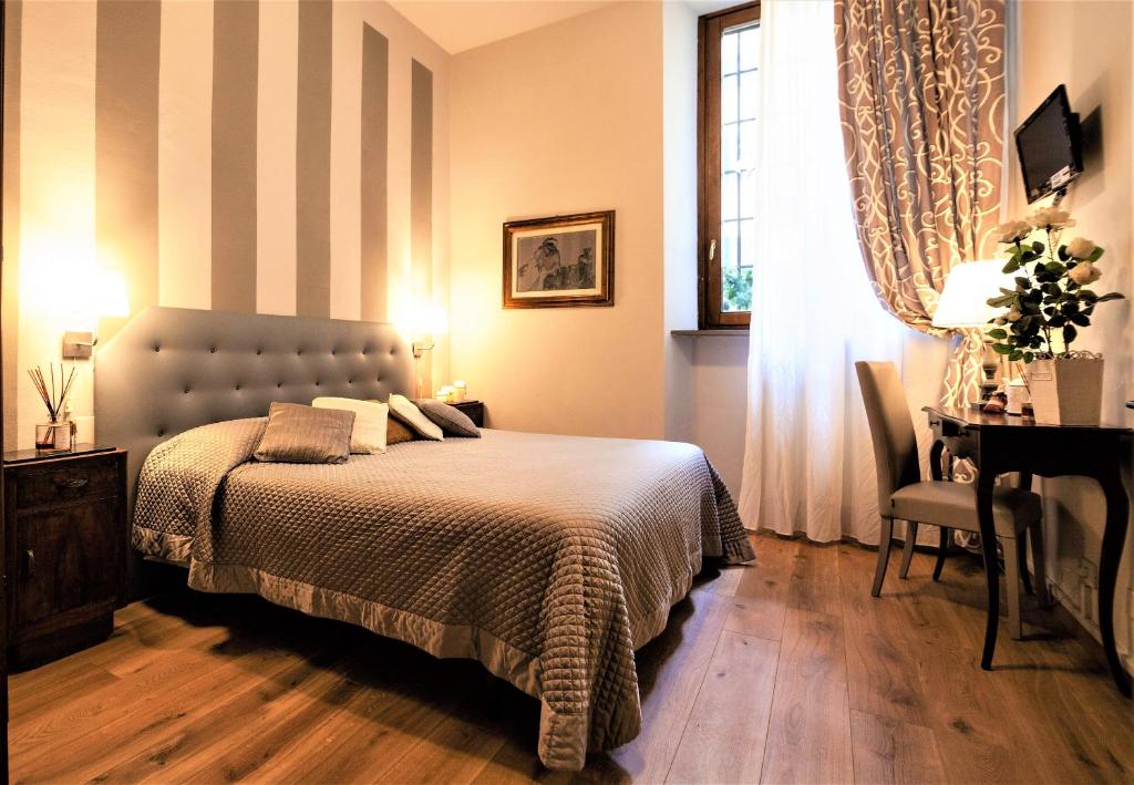 a bedroom with a bed and a desk and a window at La Colonna (Historic Centre) in Lucca