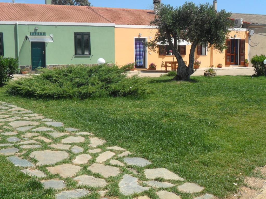 a house with a cobblestone path in front of a yard at Agriturismo Ezzi Mannu in Stintino