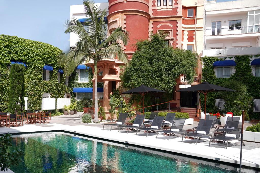 una piscina con sillas y sombrillas frente a un edificio en Hotel Medium Sitges Park, en Sitges