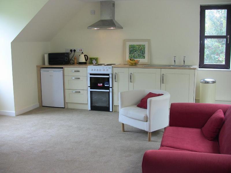 a living room with a couch and a red chair at The Garden Apartment in Dunino