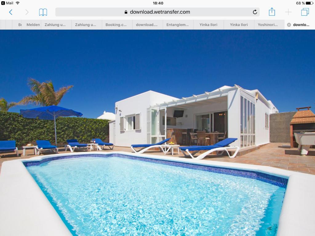 a villa with a swimming pool in front of a house at Villa hermosa in Puerto del Carmen