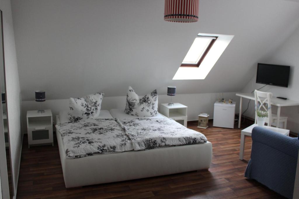 a white bedroom with a bed and a skylight at Pension Dräger in Mühl Rosin