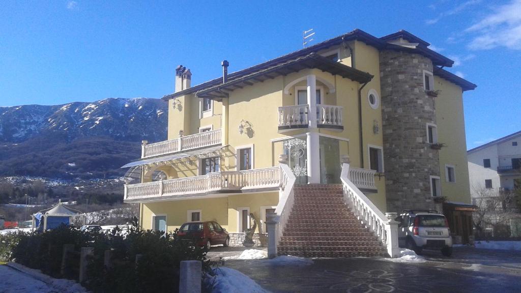 a large yellow building with stairs in front of it at Hotel Vitalba in Rocca di Mezzo