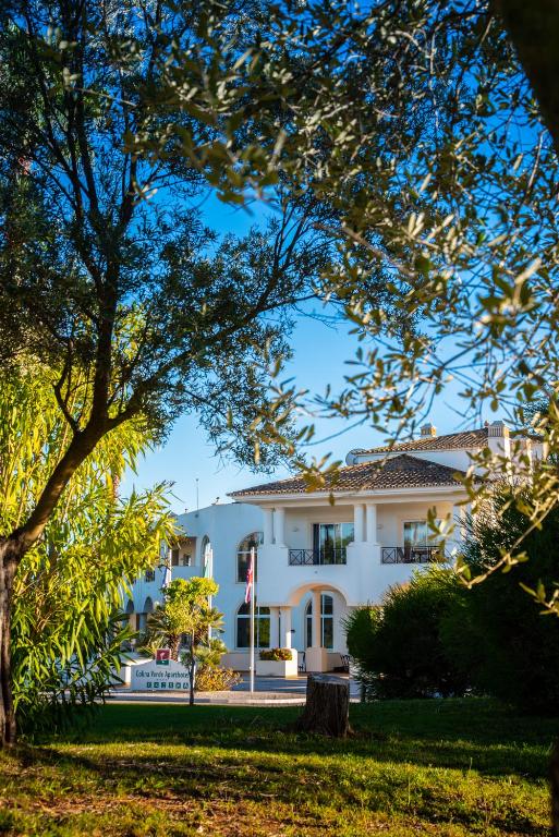 a large white building with a tree in the foreground at Colina Verde Resort in Moncarapacho