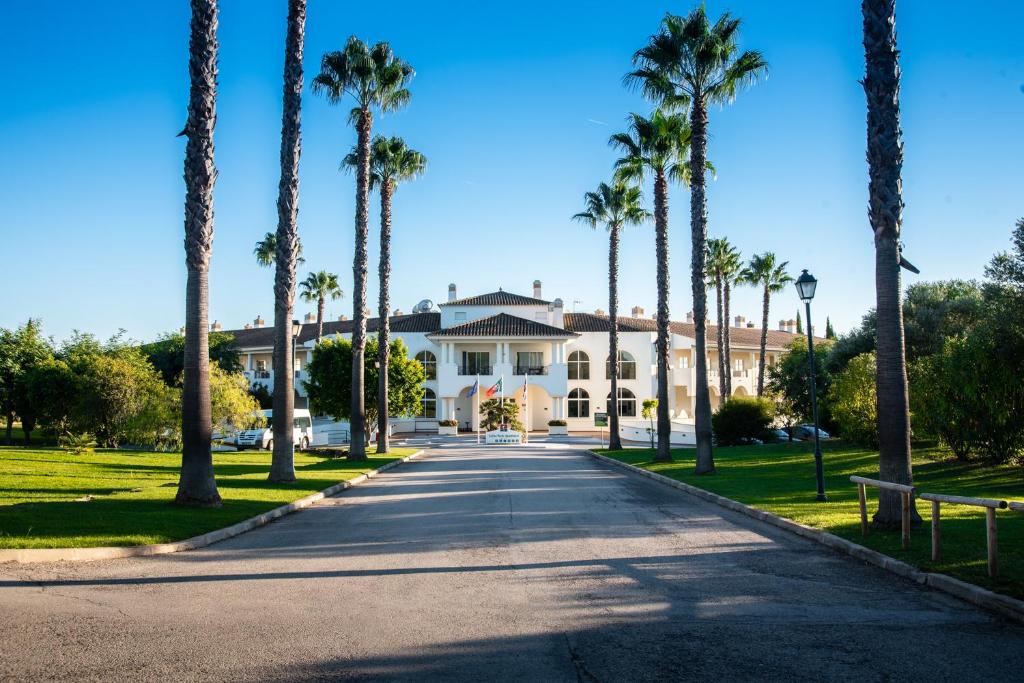 a large white house with palm trees on a street at Colina Verde Resort in Moncarapacho
