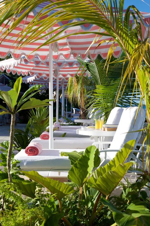 a group of white lounge chairs under an umbrella at Cobblers Cove - Barbados in Saint Peter