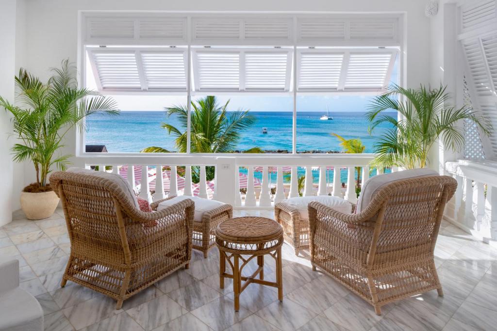 a room with a balcony with a view of the ocean at Cobblers Cove - Barbados in Saint Peter