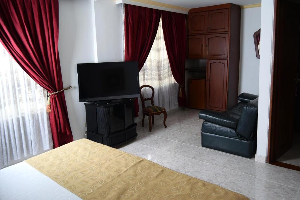 a room with a bed and a television and a couch at Hotel Bolivar Plaza in Manizales