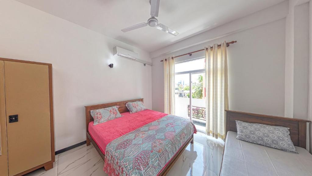 1 dormitorio con cama roja y ventana en Ocean Breeze Apartment Colombo, en Colombo