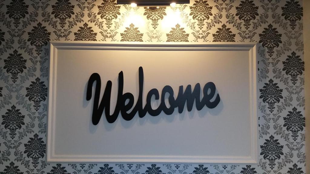 een witte fotolijst met het woord welkom op een muur bij Welcome Apartment in Timişoara