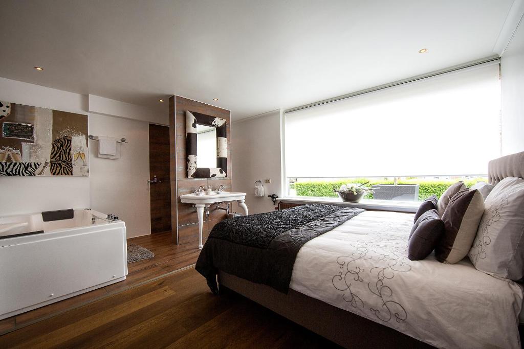a bedroom with a bed and a bathroom with a tub at Villa BBB in Oosterhout