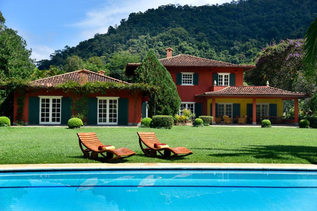 une maison avec deux chaises et une piscine dans l'établissement Maison de Campagne, Chambres D'Hôtes - Itaipava, à Itaipava