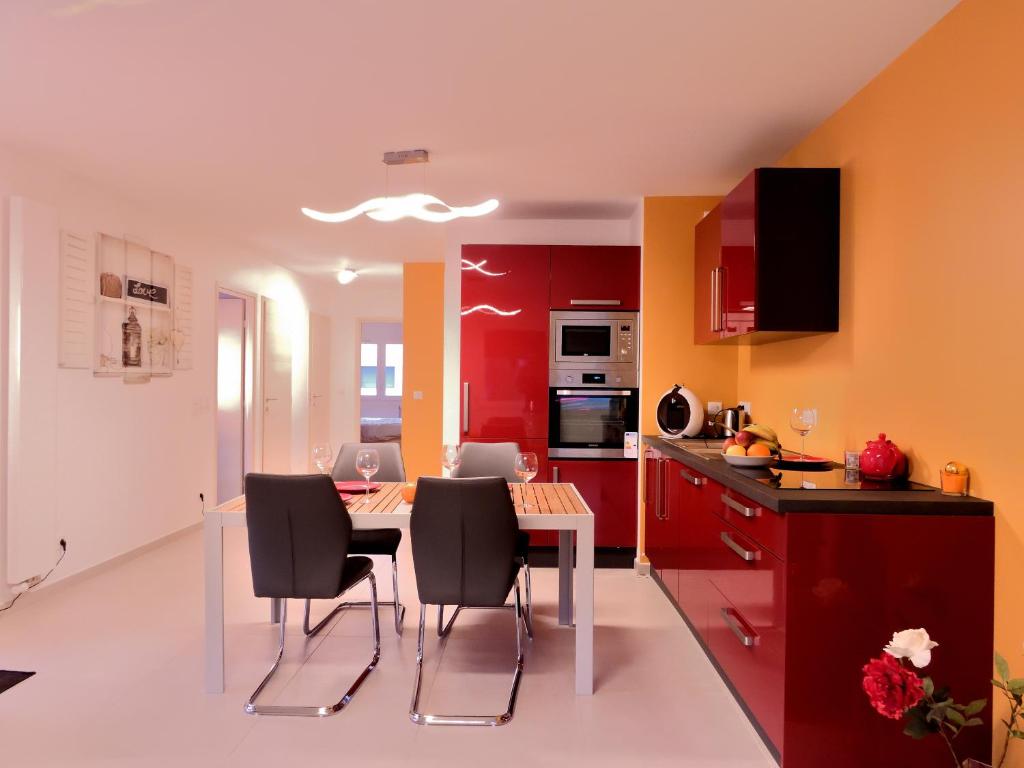 安錫的住宿－LE LYRIQUE，厨房配有红色橱柜和桌椅