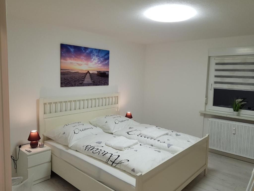 a white bed in a white bedroom with a picture on the wall at Ferienwohnung Cifci in Friedrichshafen