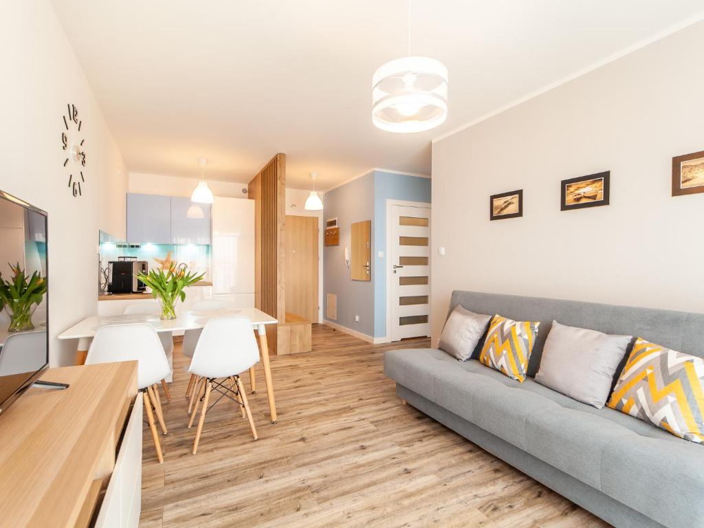 salon i kuchnia z kanapą i stołem w obiekcie Apartament Rybacka 12A/68, Kołobrzeg w Kołobrzegu