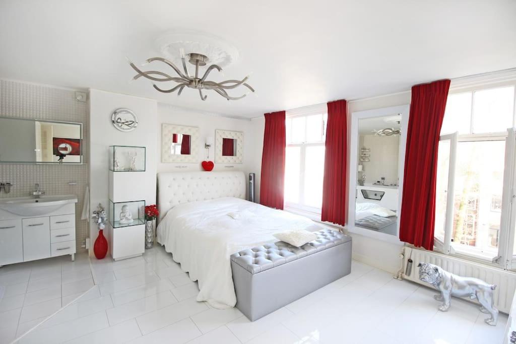 a white bedroom with a large bed and a bathroom at White Luxury Penthouse in City Centre in Amsterdam