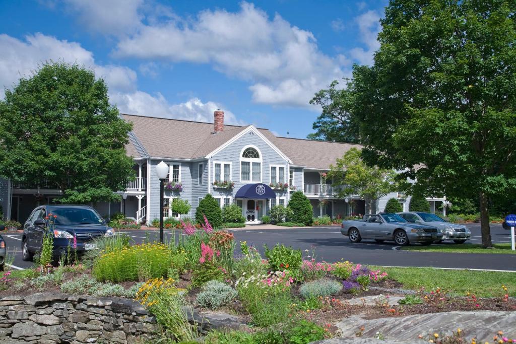 ein weißes Haus mit Autos auf einem Parkplatz in der Unterkunft Cod Cove Inn in Edgecomb