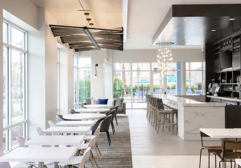 ein Restaurant mit weißen Tischen und Stühlen und Fenstern in der Unterkunft Hyatt Place Sandestin at Grand Blvd in Destin
