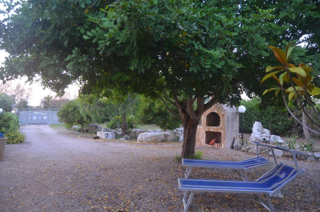 2 chaises bleues assises sous un arbre dans un parc dans l'établissement Villetta Sakapo', à Corigliano dʼOtranto