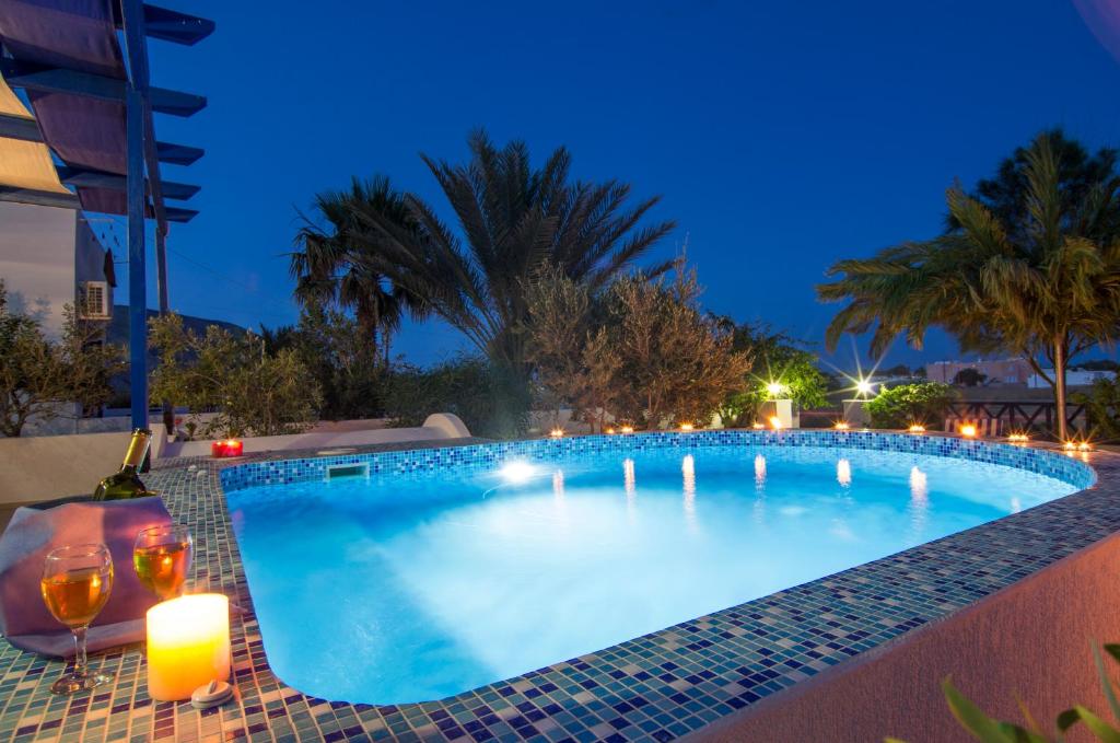 a swimming pool at night with candles and wine glasses at White & Blue in Perivolos