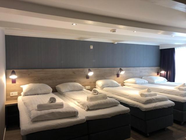 a room with three beds with white pillows on them at Facade Hotel Amsterdam in Amsterdam