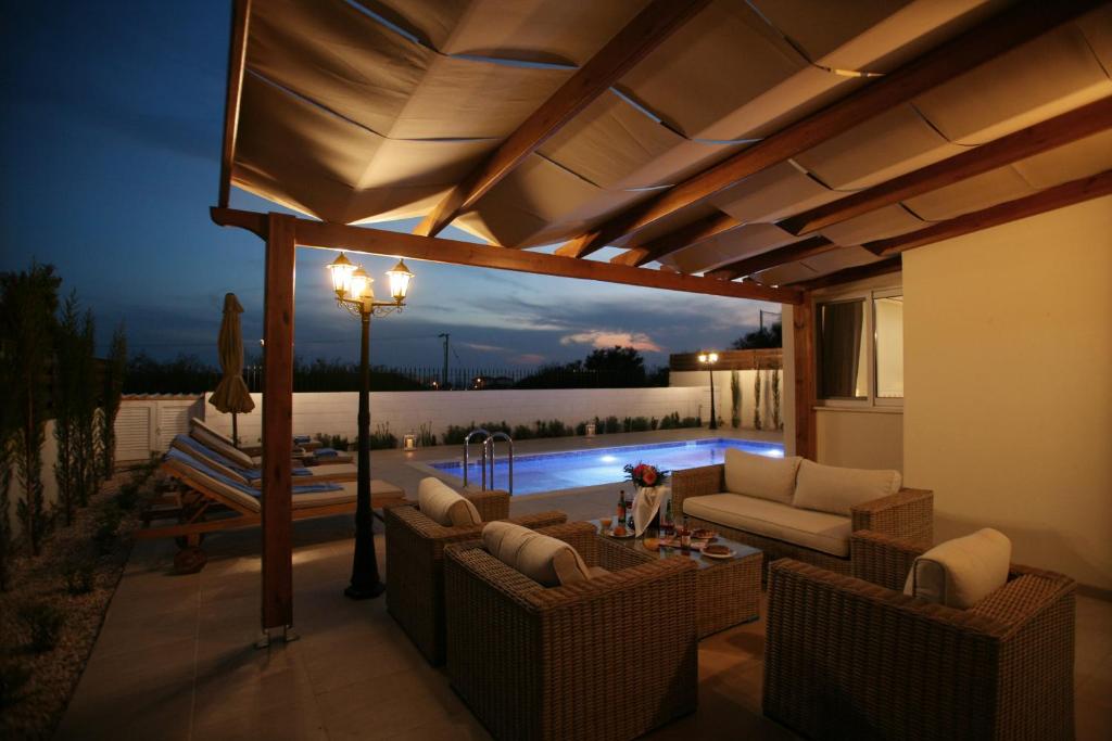 a patio with two couches and a deck with a pool at Villa Carmel in Ayia Napa