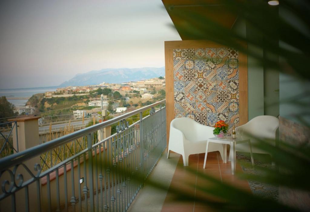 balkon z białym krzesłem i stołem z kwiatami w obiekcie Villalba w mieście Balestrate