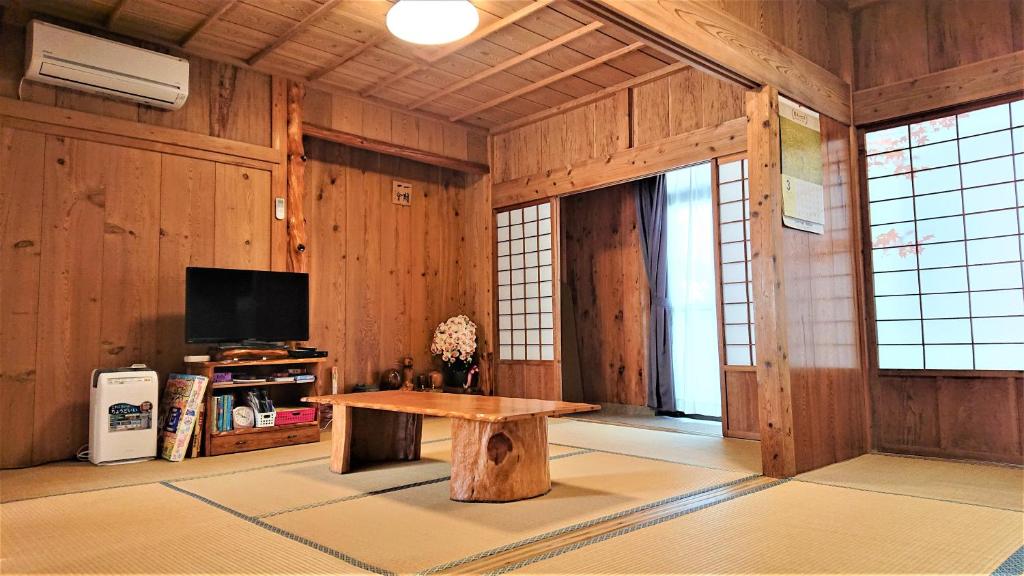 a living room with a table and a tv at Cottage Yakusugi House in Yakushima