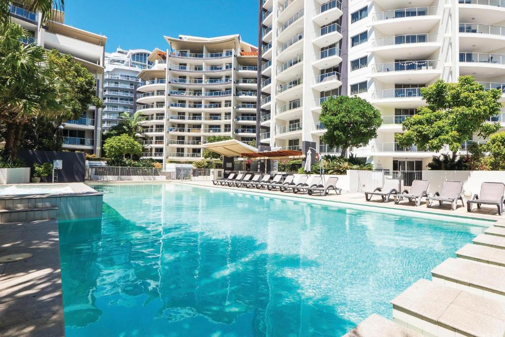 una piscina con sillas y edificios en el fondo en Trilogy Surfers Paradise, en Gold Coast