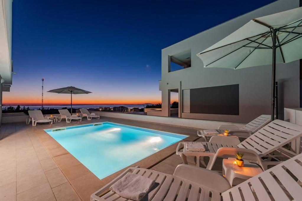 Casa con piscina con sillas y sombrilla en Dario 2. modern & luxury apartment with a pool, en Novalja