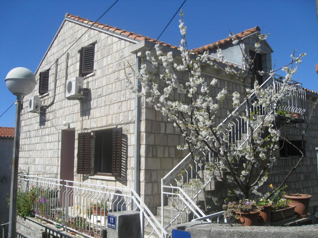 un edificio con un árbol florido delante de él en Nikolina Rooms, en Dubrovnik