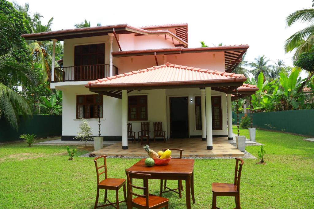 une maison avec une table et des chaises devant elle dans l'établissement White Villa Koggala, à Habaraduwa Central