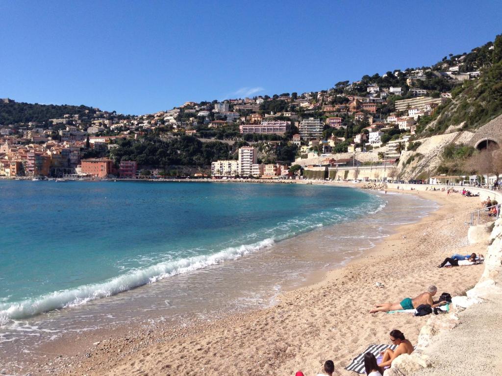un groupe de personnes allongées sur une plage dans l'établissement Nyrenoverad lägenhet med havsutsikt, à Villefranche-sur-Mer