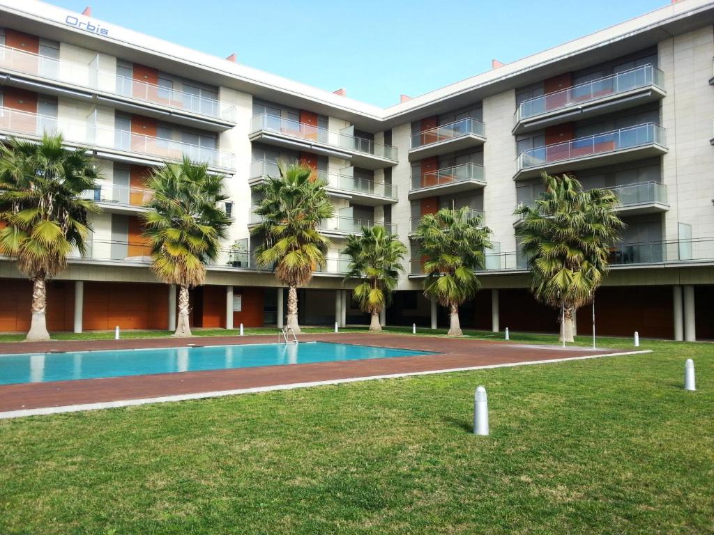 un edificio de apartamentos con piscina y palmeras en Apartamento Playa Esquirol, en Cambrils