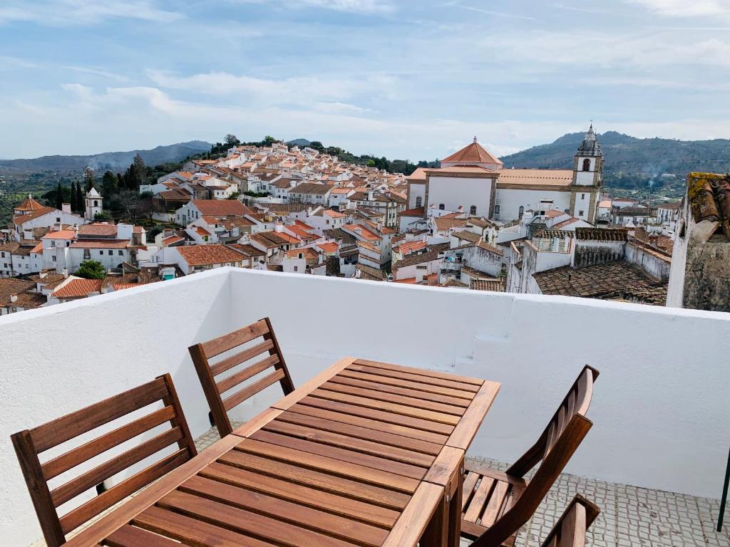 a wooden table and chairs on a balcony with a city at Casa do Castelo in Castelo de Vide