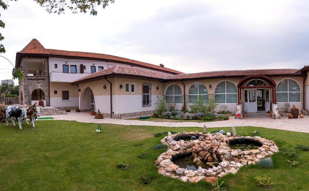 una casa grande con una estatua en el patio en Hanul Hora Romaneasca- camere de inchiriat, en Eforie Sud